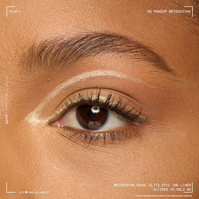 A close-up macro shot of a person's eye, with a gold eyeliner expertly applied along the waterline and inner corner, showcasing the product's finish on skin in shade 02 Glitzed In Gold